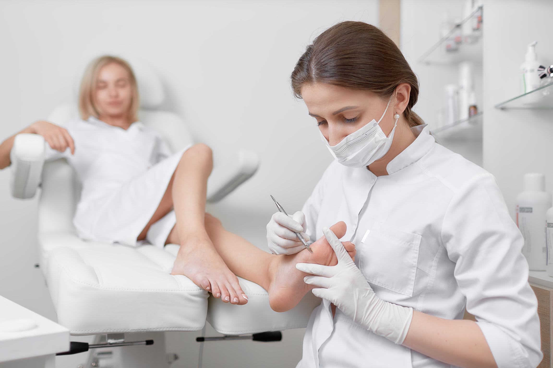 Podiatrist doctor caring about client foot with special iron tool